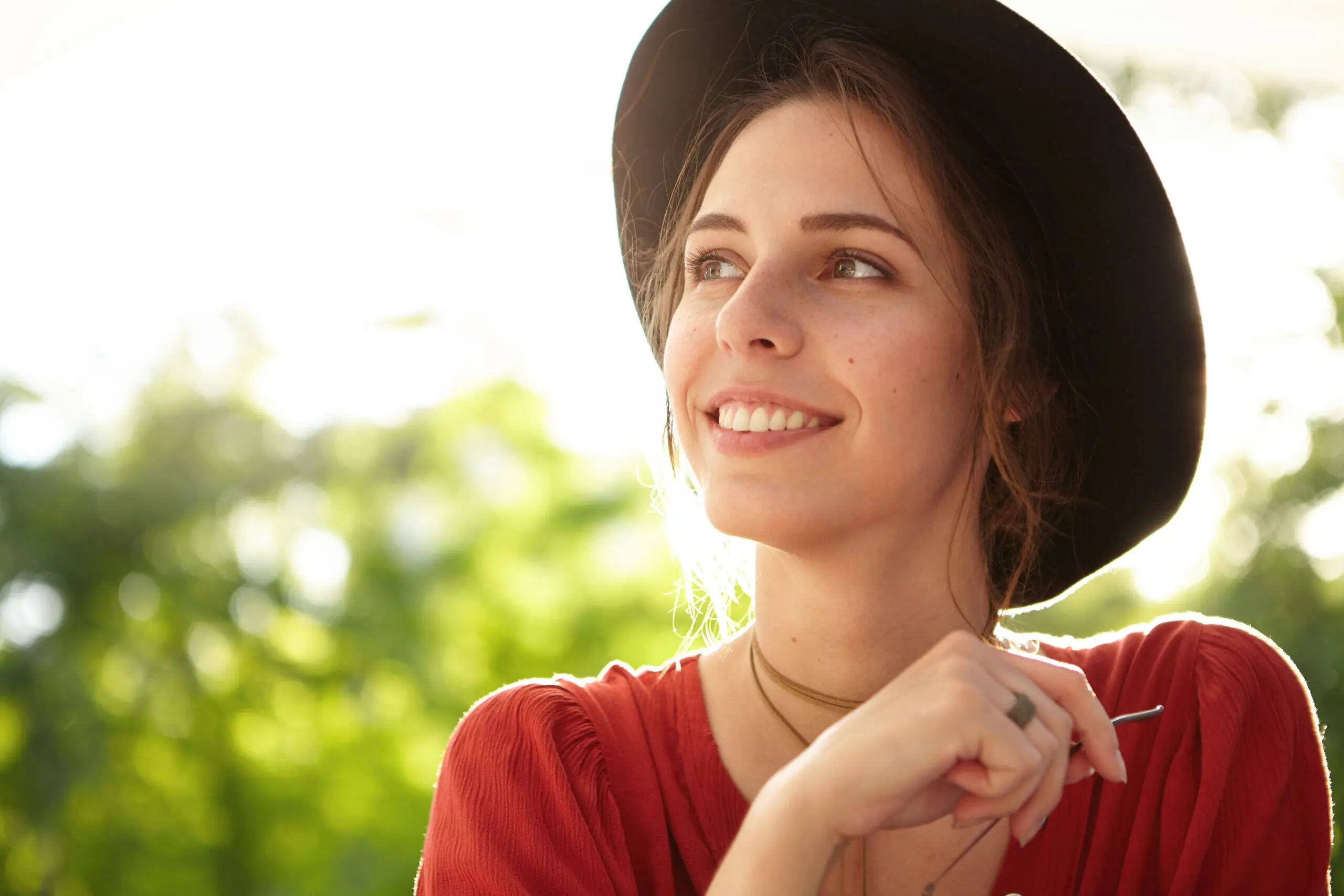 Smiling woman wearing a hat outdoors in natural light
