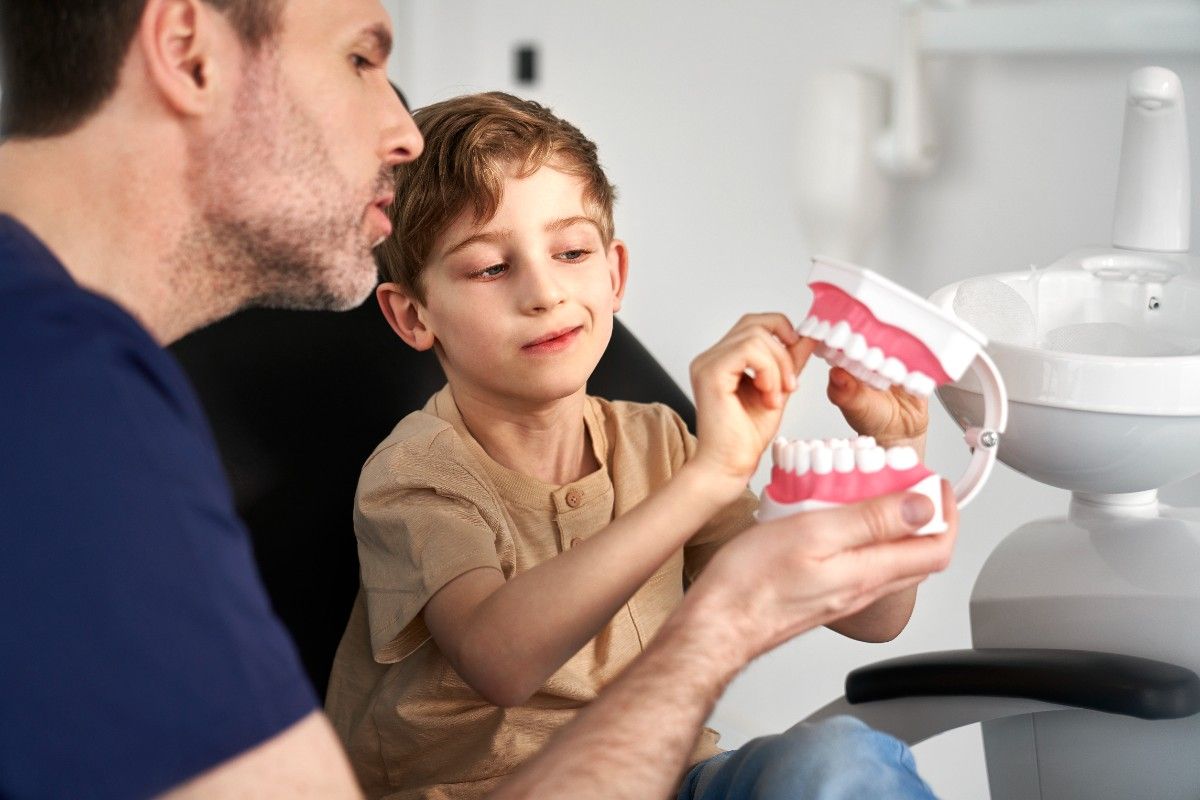 Child learning about dental hygiene with tooth model at clinic
