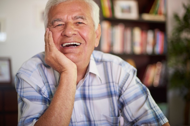 Senior man smiling while touching his jaw